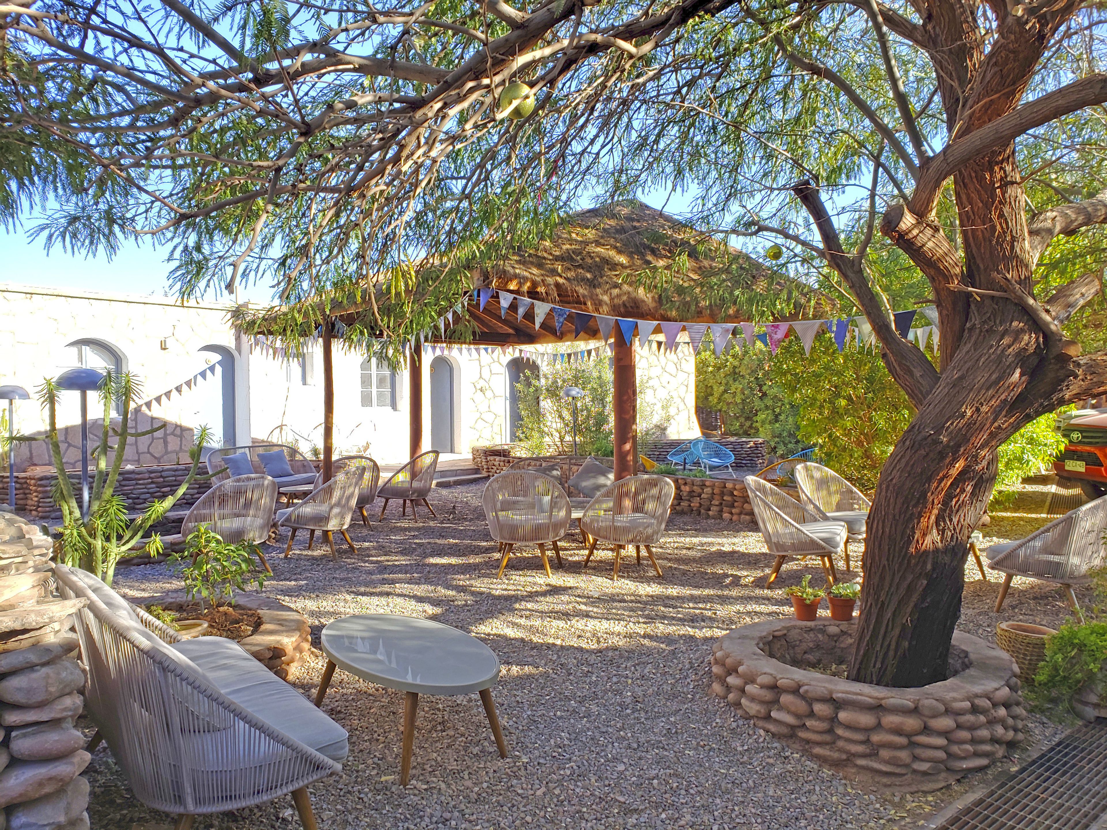 Eine Terrasse mit Korbmöbeln, einer Steinmauer und einer Pergola mit Wimpelgirlande.
