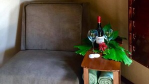 A room with a bed, a small wooden table with a bottle of wine, two glasses, and a decorative plant. There are three framed pictures on the wall. - Yocamatsu (Caye Caulker)