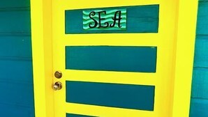 A yellow door with a green sign that reads "SEA". - Yocamatsu (Caye Caulker)