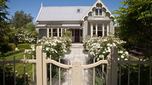 Een Victoriaans huis met een symmetrische gevel, een centrale ingang en een verzorgde tuin met witte rozen.