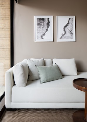 A modern living room with a white sofa, multiple cushions, and two abstract art pieces on the wall. - ATTIK SUPERIOR+BALCONY 402 (Bogotá)