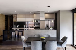 A modern kitchen with a central island, bar stools, and a dining table with chairs. - ATTIK SUPERIOR+BALCONY 402 (Bogotá)