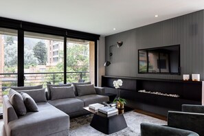 A modern living room with a sectional sofa, a coffee table, and a flat-screen TV mounted on a wall with vertical paneling.