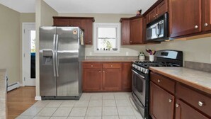 Una cocina moderna con electrodomésticos de acero inoxidable, armarios de madera y piso de baldosas.