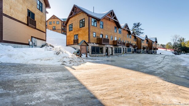 Un hilera de edificios de estilo rústico de troncos, con una entrada central, rodeada de nieve.