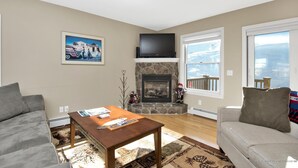 Una sala de estar con chimenea, un televisor de pantalla plana y un ventanal con vistas.