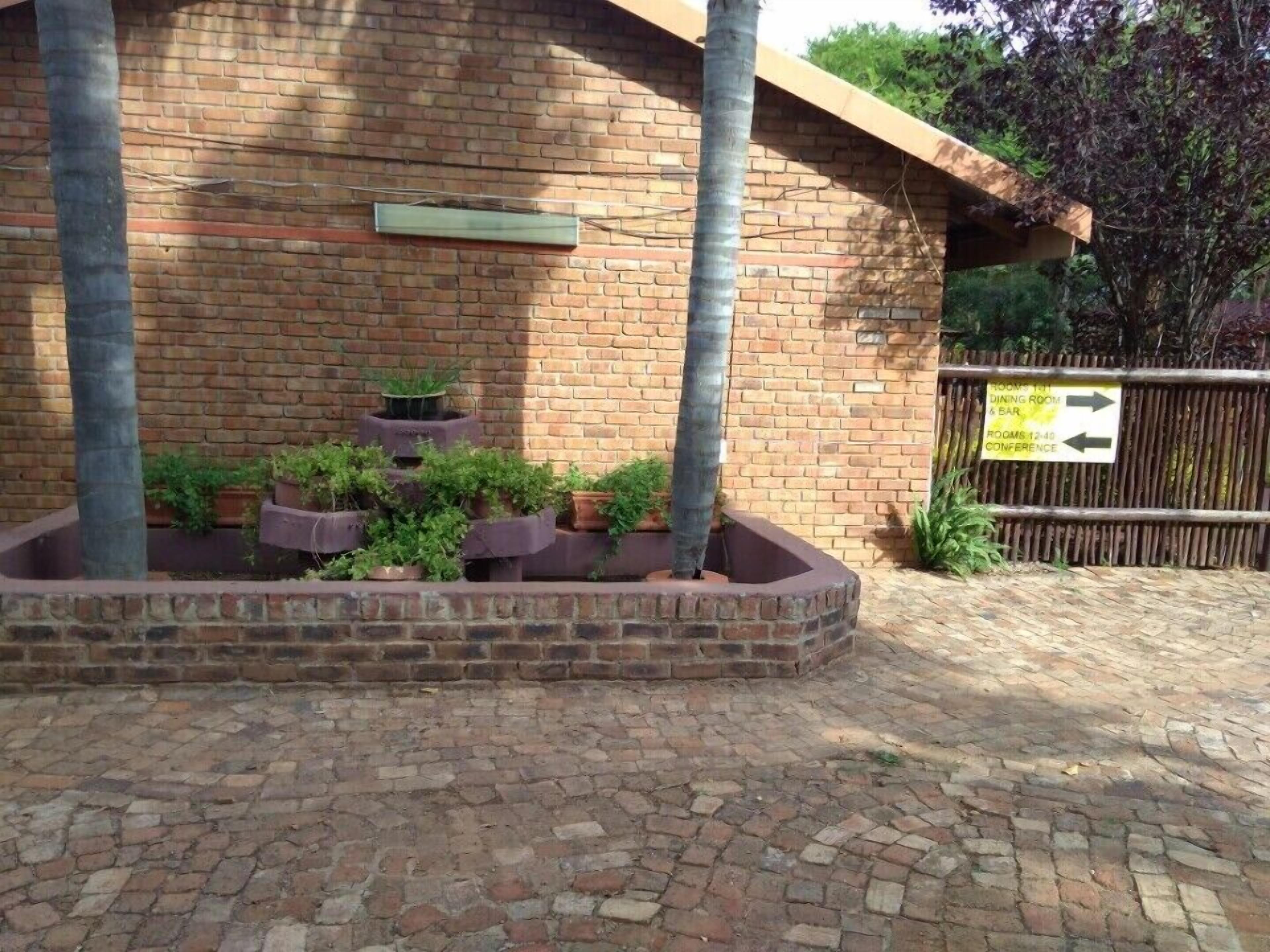 A brick building with a brick planter filled with plants.