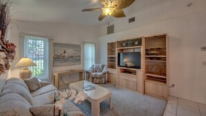Una sala de estar moderna con un sofá, un sillón reclinable, una mesa de centro, un televisor y estanterías empotradas.