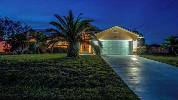 Una casa residencial con garaje número 1147, un césped bien cuidado y una palmera.