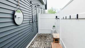 A patio with a wooden table, a small bench, and a potted plant. - Remodeled Home Near Beach and Downtown (Manistee)