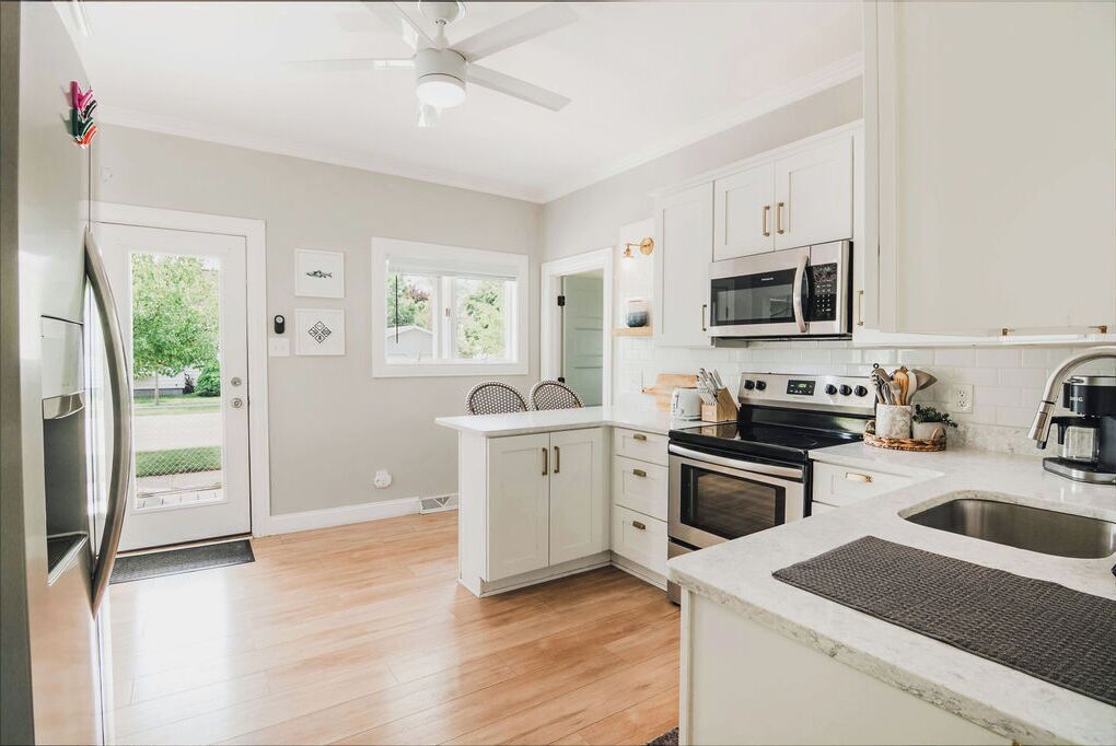 A modern kitchen with white cabinets, a stainless steel microwave, and a large oven.