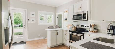 A modern kitchen with white cabinets, a stainless steel microwave, and a large oven.