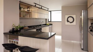 A modern kitchen with a central island, black countertops, stainless steel appliances, and wooden cabinetry. - NEW DESIGN DUPLEX - BOGO64 303 (Bogotá)