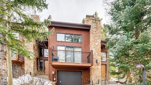 A modern two-story house with a stone facade, a balcony with a metal railing, and a garage door. - Walk to Lift: Townhome w/ Shuttle in Breckenridge! (Breckenridge)
