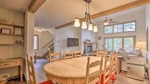 A dining area with a wooden table and chairs, a ceiling fan, and a fireplace. - Walk to Lift: Townhome w/ Shuttle in Breckenridge! (Breckenridge)