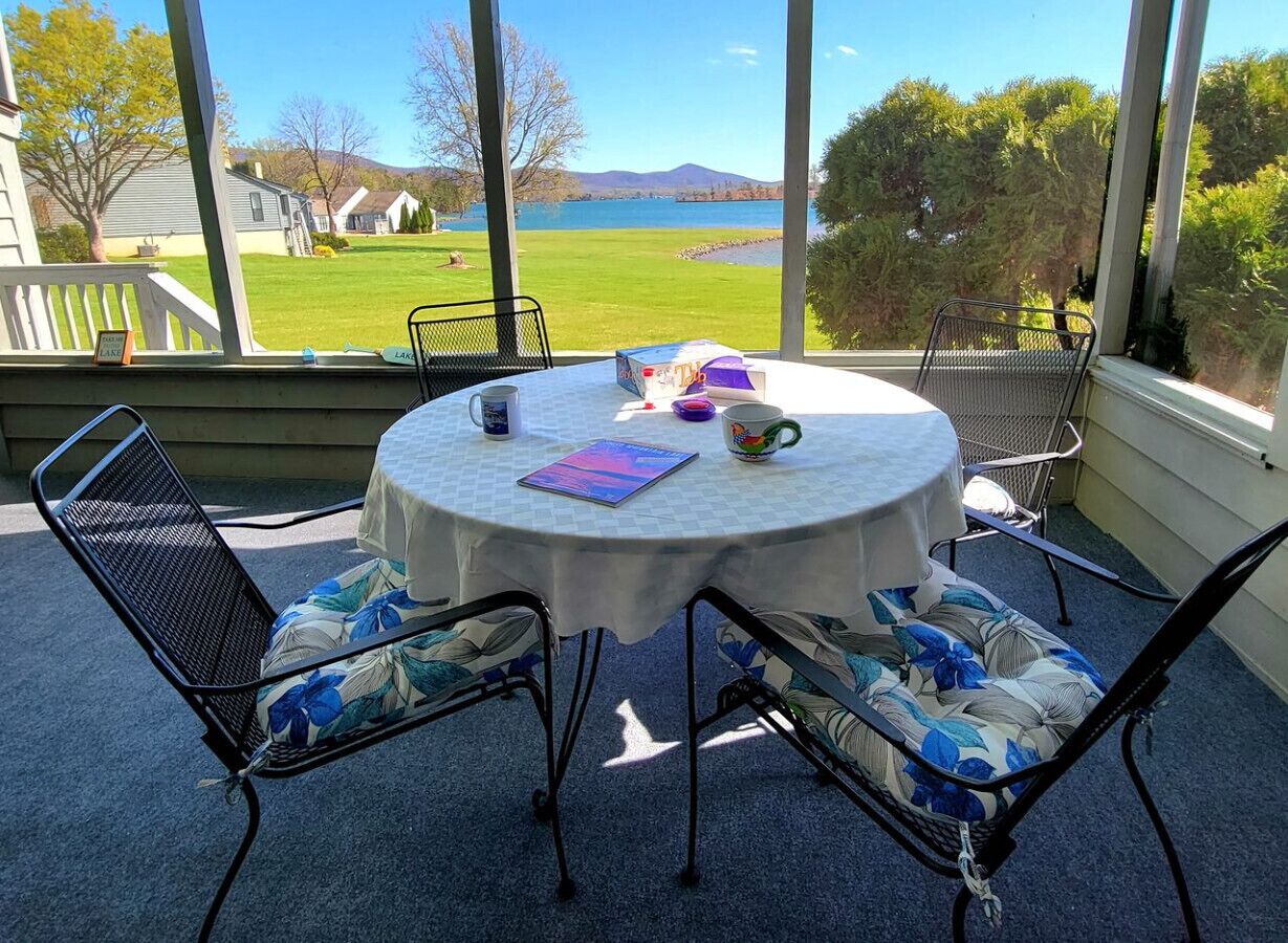 A round table with a white tablecloth, surrounded by four chairs with floral cushions, set on a blue carpeted floor.