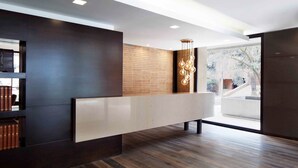 Uma área de recepção moderna com um painel de madeira decorativo, um balcão de recepção espaçoso e uma luminária pendente.