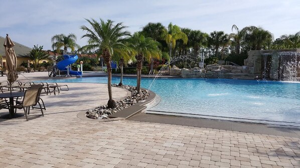 Relax by the resort pool surrounded by palm trees and a waterfall.