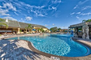 Relax by the resort pool, surrounded by a paved walkway and shaded seating areas.