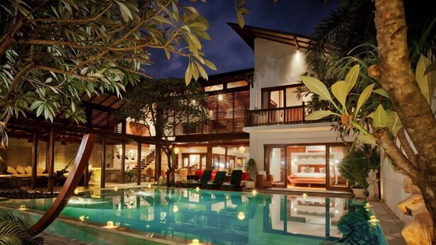 Un hotel moderno con piscina, zona de estar al aire libre e interiores bien iluminados.
