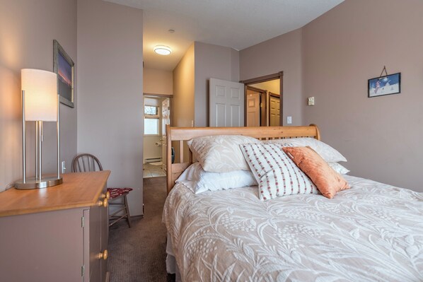 Une chambre à coucher avec un lit, une table de chevet, une lampe et une chaise.