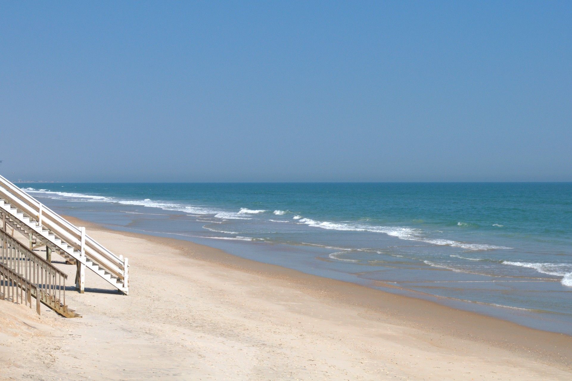 A beach with a staircase leading down to the shore.