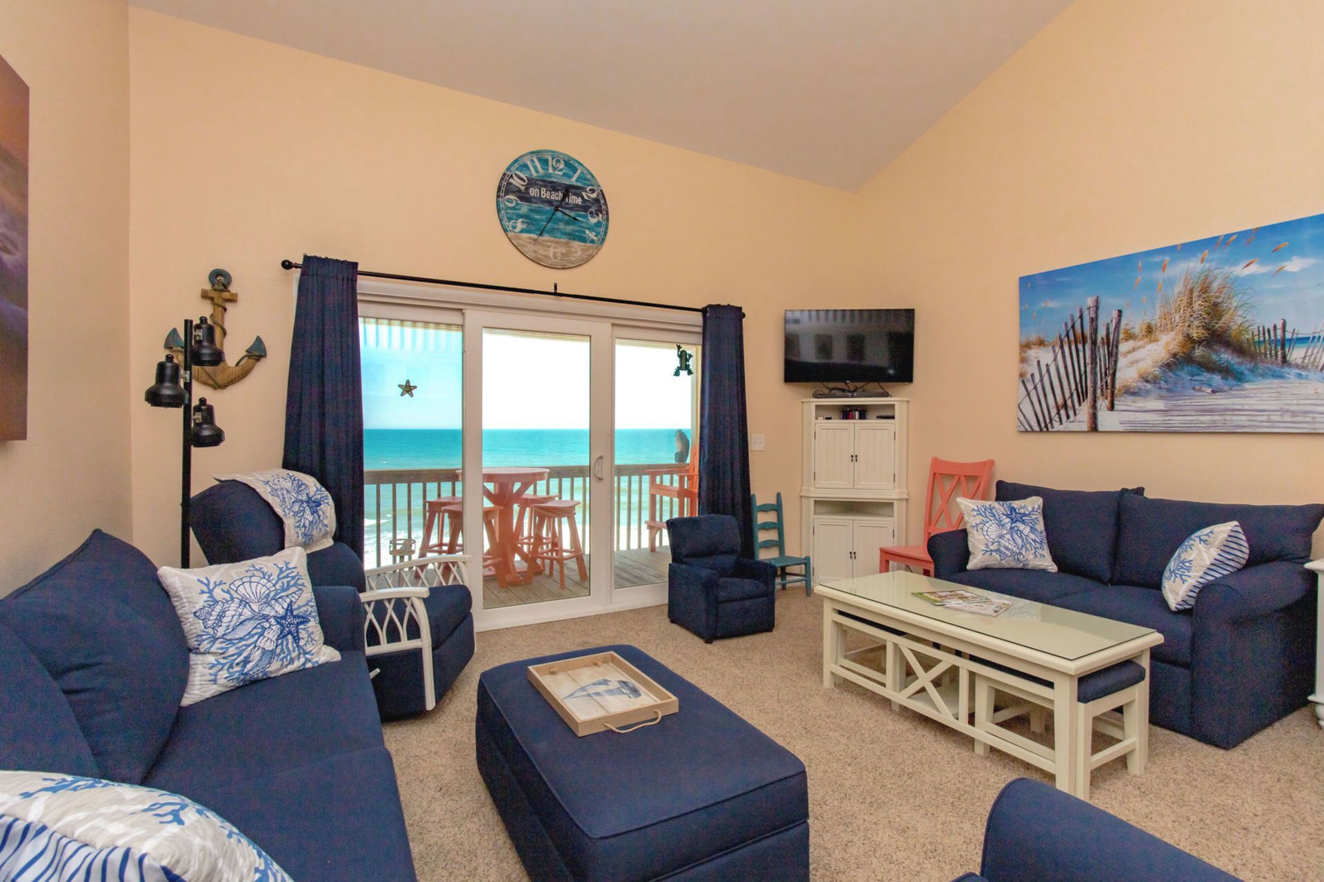 A living room with a view of the ocean, a clock, and a painting.