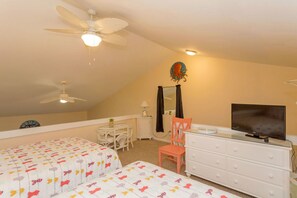 A bedroom with two beds, a ceiling fan, a television, a dresser, and a mirror.