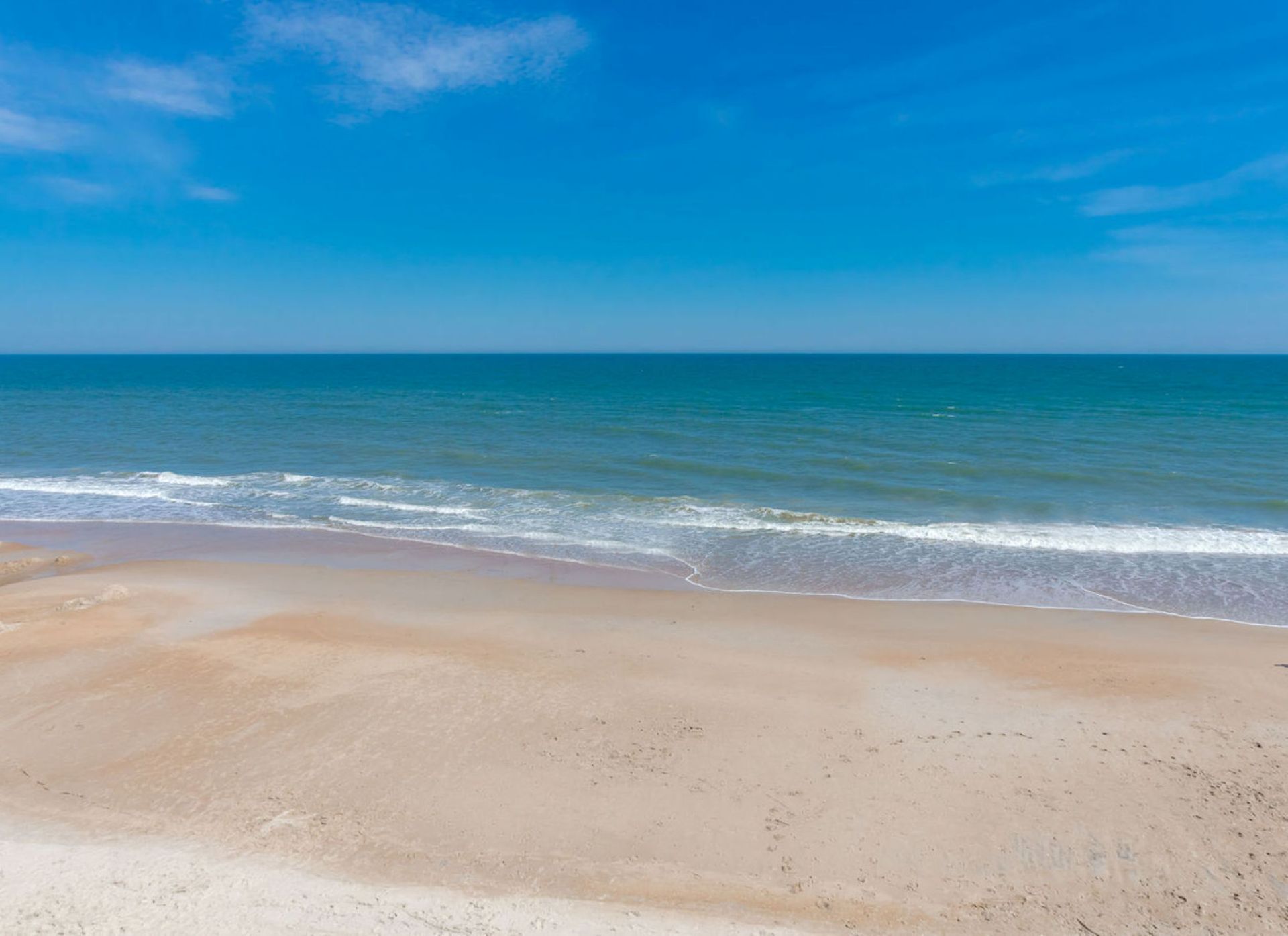 Een strand met een heldere lucht en een rustige zee.