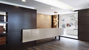 Una recepción moderna con un mostrador alargado, un revestimiento de pared de madera y un ventanal con vistas al exterior.