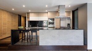 Una cocina moderna con una isla central, electrodomésticos integrados y una pared decorada con ladrillos.