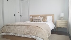 A bedroom with a bed, a nightstand, a lamp, and a door.