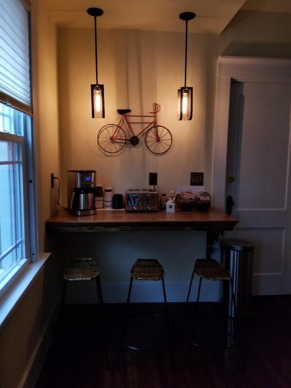 A kitchen area with a wooden countertop, two stools, a hanging bicycle decoration, and a coffee machine. - Spacious 2 Bedroom apartment close to Yale Bowl (New Haven)