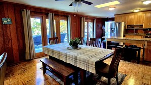 A dining area with a wooden table, benches, and chairs. There is a kitchen area with wooden cabinets and appliances. - Gus`s Getaway- Dog friendly home with huge dock with electricity - pool table and old school juke box (Huddleston)