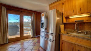 A kitchen with wooden cabinets, a stainless steel refrigerator, a sink, and a view of a pool through the sliding glass doors. - Gus`s Getaway- Dog friendly home with huge dock with electricity - pool table and old school juke box (Huddleston)