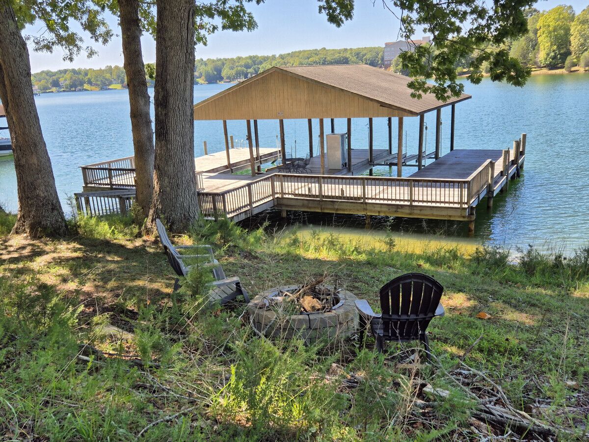 A wooden deck with a covered seating area overlooking a lake.