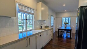 Une cuisine moderne avec des meubles blancs, un plan de travail en bois et un coin repas comprenant une table et des chaises.