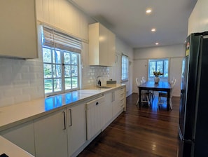 A modern kitchen with white cabinets, a wooden countertop, and a dining area with a table and chairs.