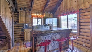 A rustic cabin interior with wooden walls, a stone bar, and red bar stools. - Rustic Cabin 20 Mins to Capitol Reef Nat'l Park! (Lyman)