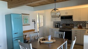 Una cocina con refrigerador azul, mesa de comedor de madera y gabinetes blancos.