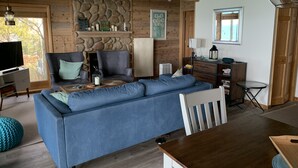 Una sala acogedora con un sofá seccional azul, una mesa de comedor de madera y una pared de chimenea de piedra.