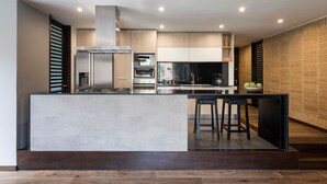 A modern kitchen with a central island, built-in appliances, and a brick accent wall. - ATTIK STUNNING SUPERIOR  301 (Bogotá)