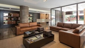 A modern living room with two brown leather sofas, a glass coffee table, and a large bookshelf. - ATTIK STUNNING SUPERIOR  301 (Bogotá)