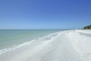 Una playa con cielos despejados y aguas tranquilas.