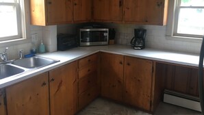 A kitchen with wooden cabinets, a stainless steel sink, a microwave, and a coffee maker. - Beach Cottage with Outdoor Patio & Grill, 8 min. Walk to Beach (Old Orchard Beach)