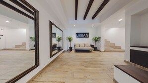 A spacious lobby with a modern design, featuring a large mirror, a sofa, and potted plants. - Extraordinary condo in Urban complex! 2BD Condo for rent in Old Town, Puerto val (Puerto Vallarta)