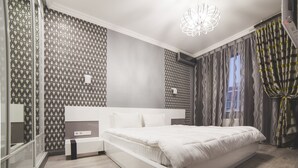 Une chambre moderne avec un grand lit, une table de chevet, un miroir et un papier peint à motifs.