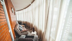 Une pièce d’angle avec un mur en briques, un fauteuil confortable agrémenté d’un vase, et une petite table.
