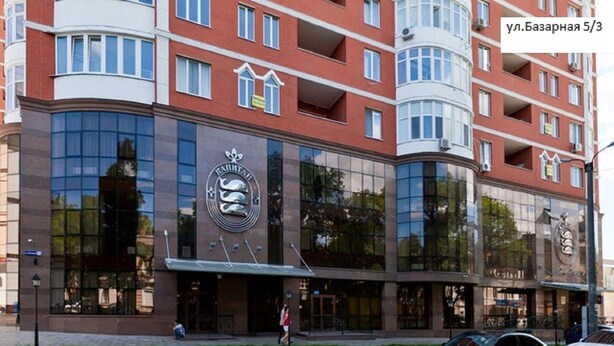 Un hôtel moderne, doté d’un logo bien visible, de grandes fenêtres en verre et d’une façade incurvée.