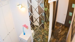 Un intérieur moderne avec un escalier en verre, un mur blanc agrémenté d’un luminaire et un tableau.